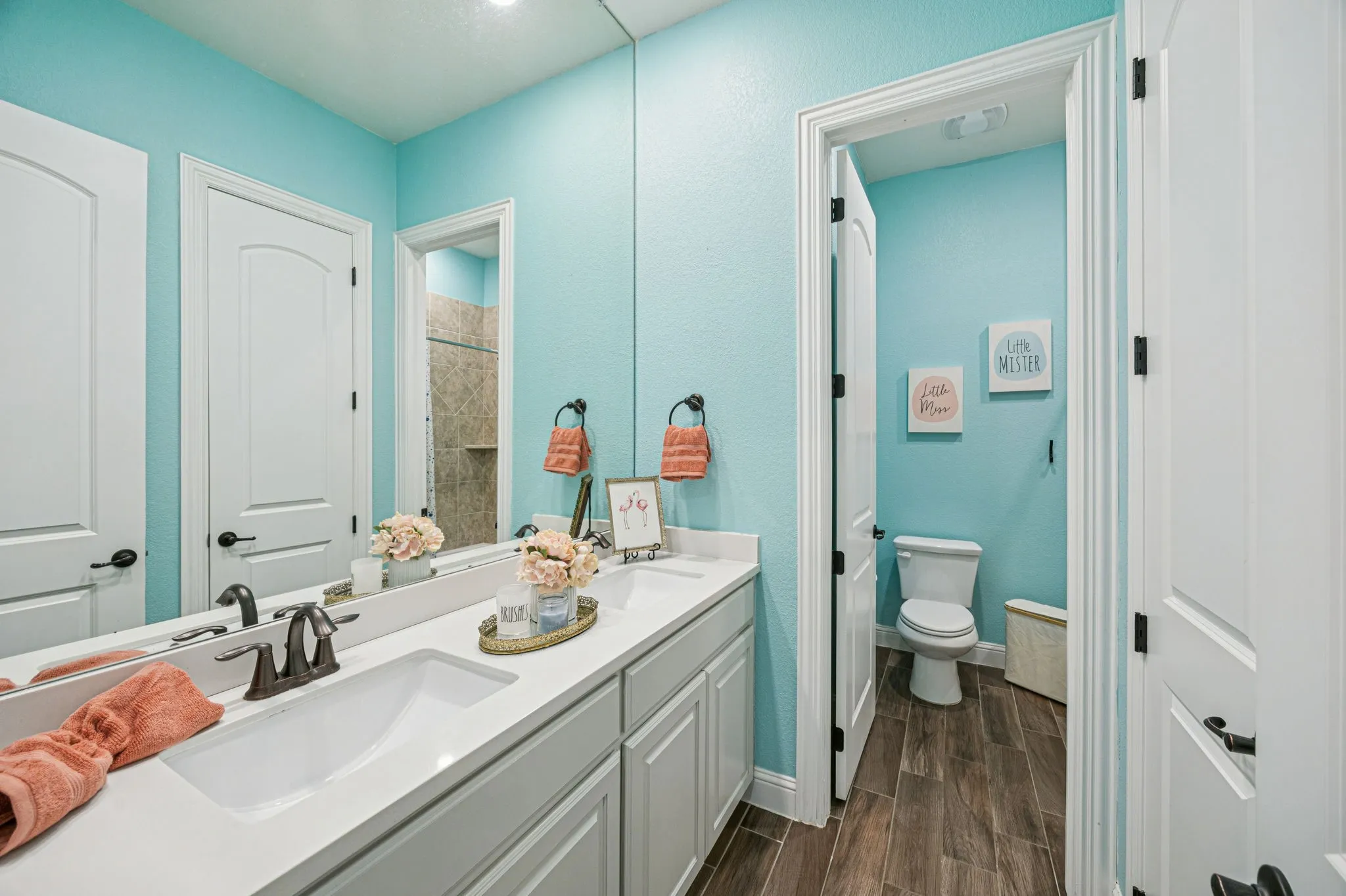 Double vanity with integrated sinks, wood-finish flooring, and a separate water closet