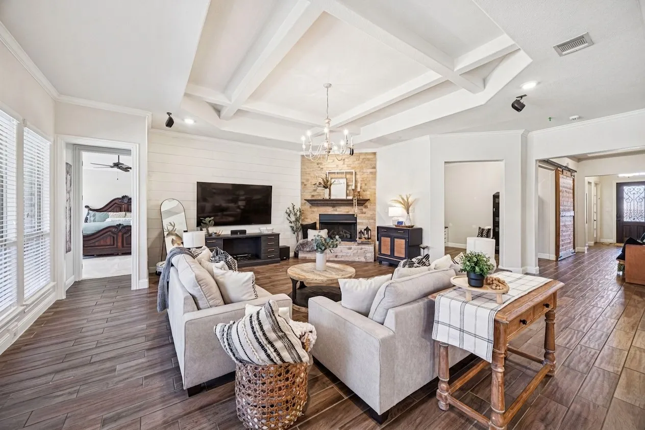 Coffered ceiling, wood-finish flooring, stone fireplace, shiplap accent wall, and decorative barn doors