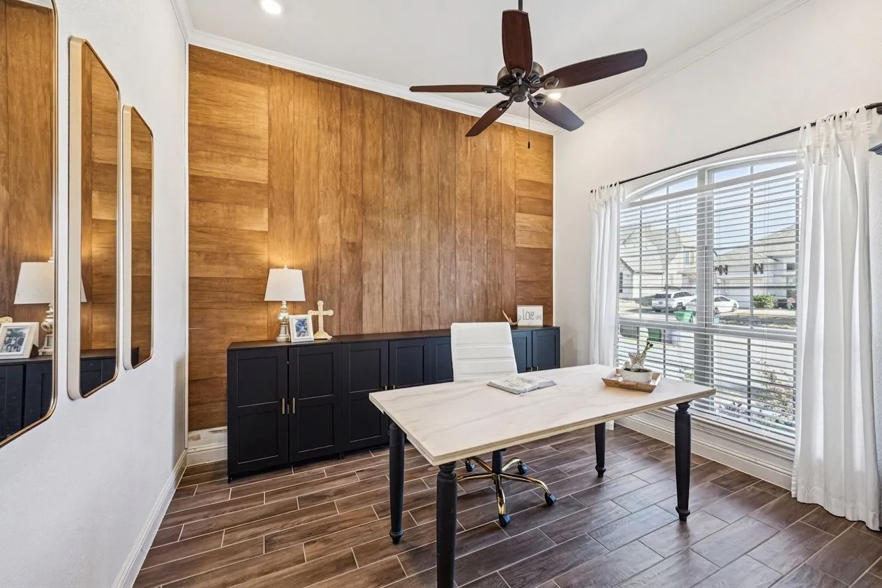Wood-finish accent wall, vaulted ceiling with a ceiling fan, arched window with horizontal blinds, built-in black cabinetry, and wood-finish tile flooring