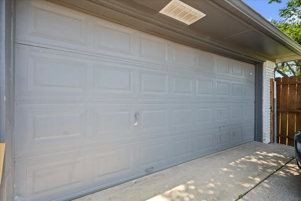Panel-style garage door with concrete driveway and brick siding