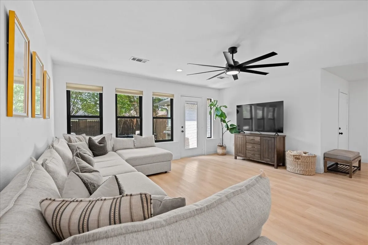 Recessed lighting, wood-finish flooring, a modern ceiling fan, multiple windows, and a glass-paneled door