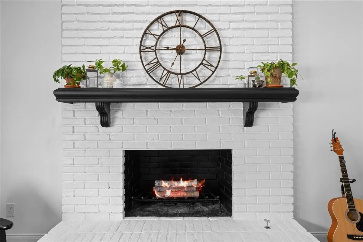 White-painted brick fireplace with a black wood mantel and hearth