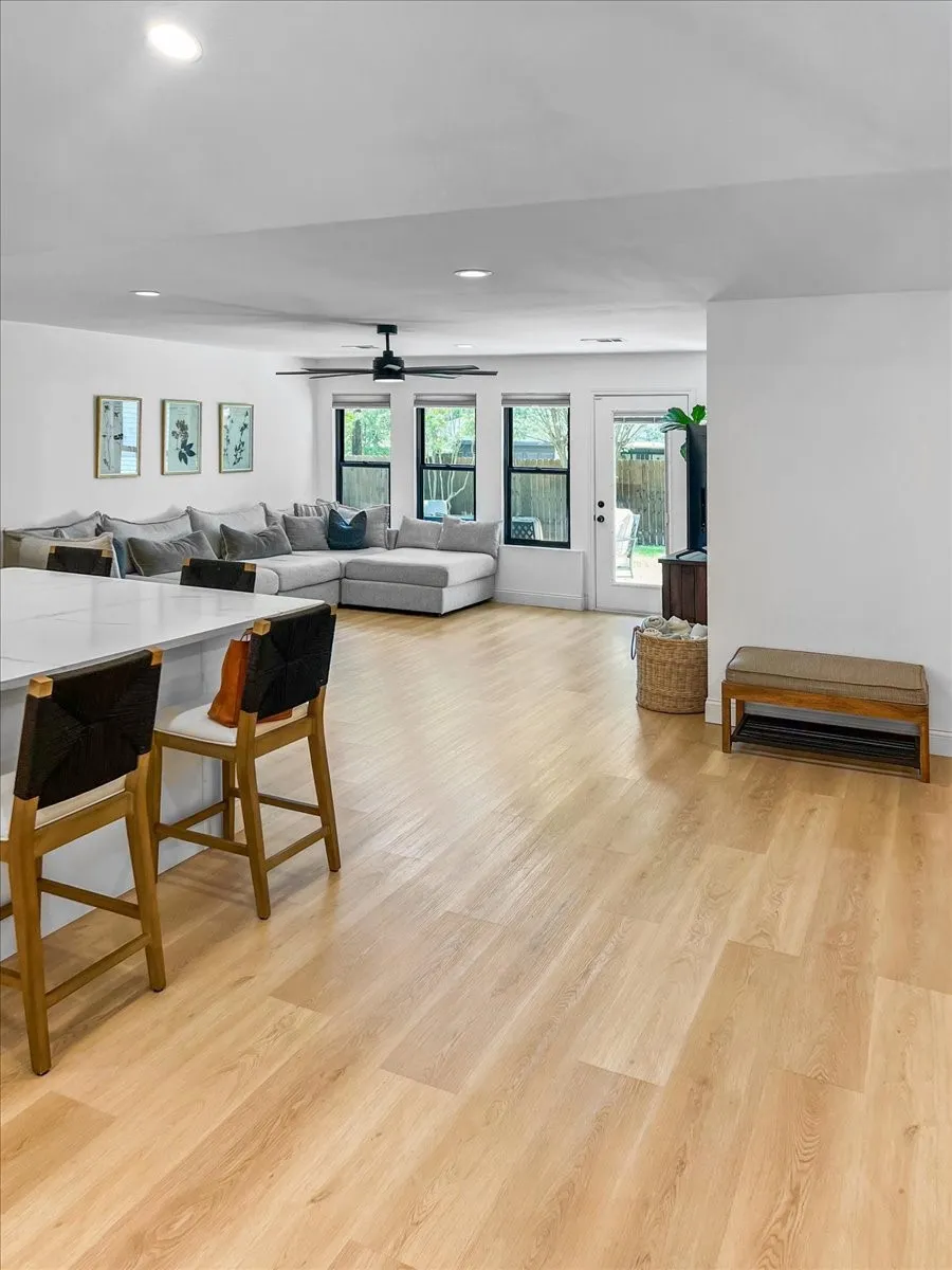 Open-concept living space featuring light wood-finish flooring, recessed lighting, and a contemporary ceiling fan