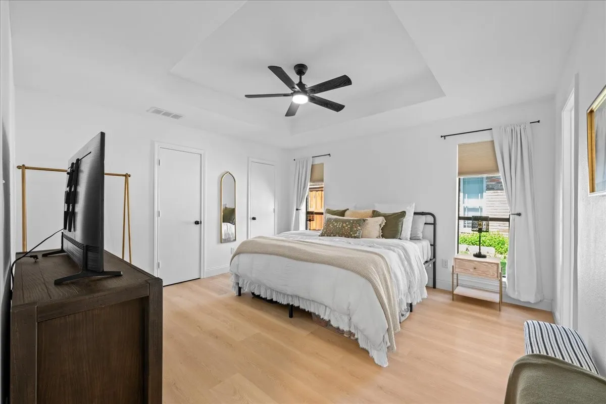 2nd Primary Bedroom has tray ceiling with a black ceiling fan, light wood-finish flooring, and white interior doors