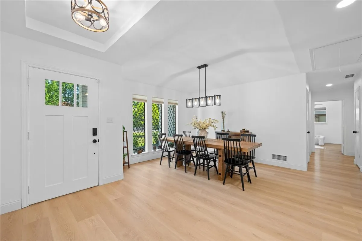 Light wood-finish flooring with a white paneled entry door