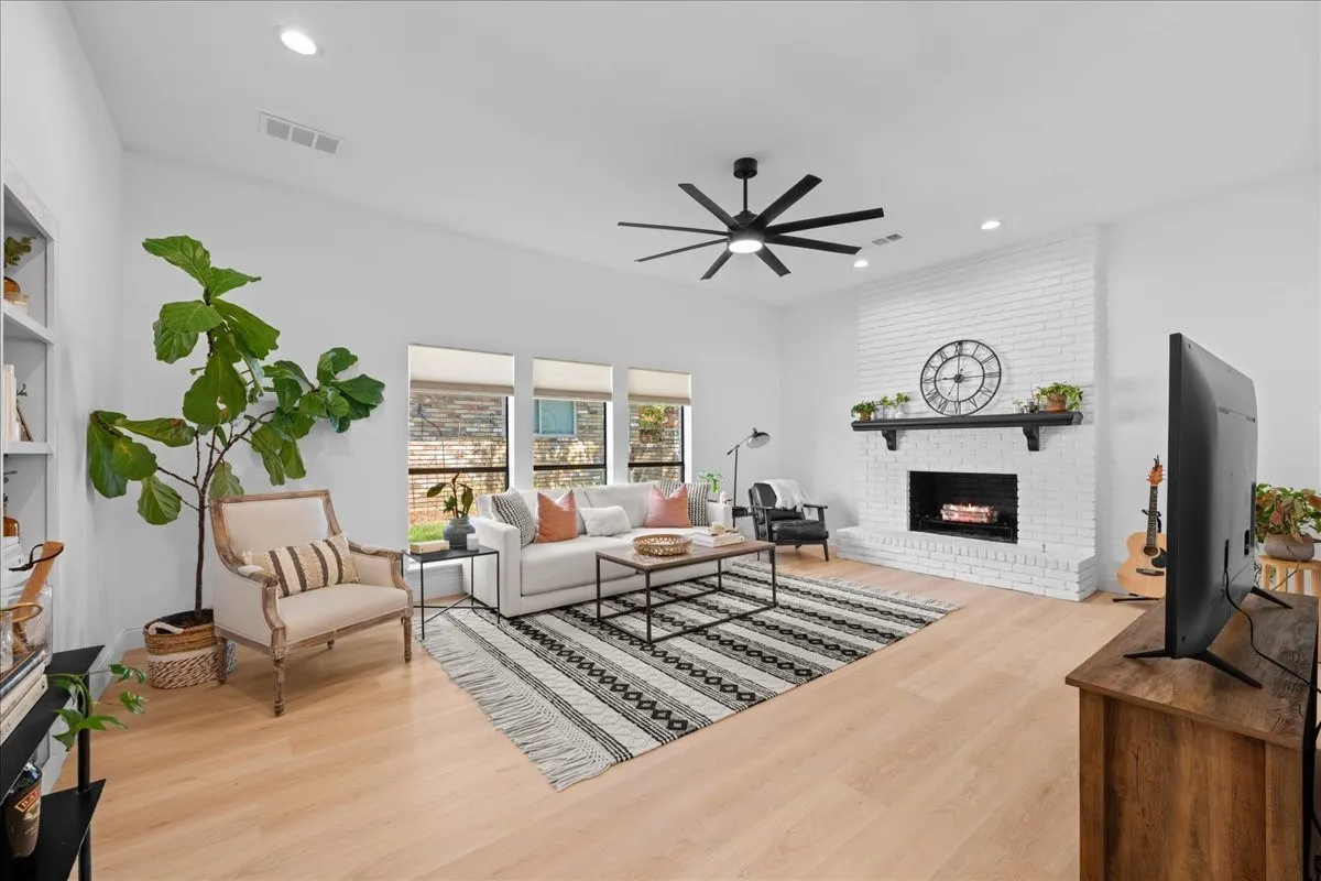 Living area featuring a painted brick fireplace, wood-finish flooring, a ceiling fan, and recessed lighting