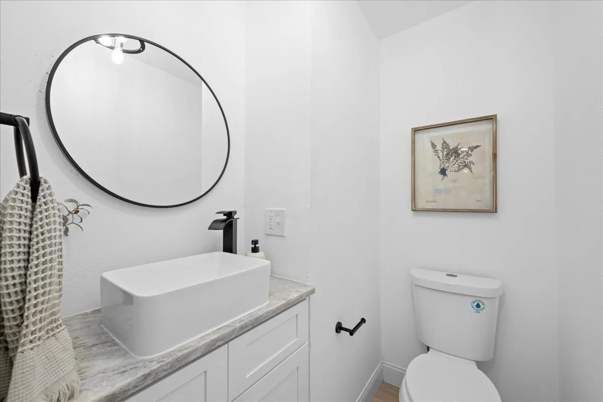 White vanity with shaker-style cabinetry, rectangular vessel sink, and matte black faucet