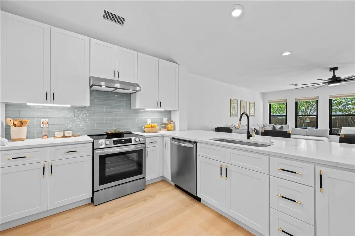 Contemporary kitchen featuring white cabinetry, light wood-finish flooring, stainless steel appliances, a light tile backsplash, and recessed lighting