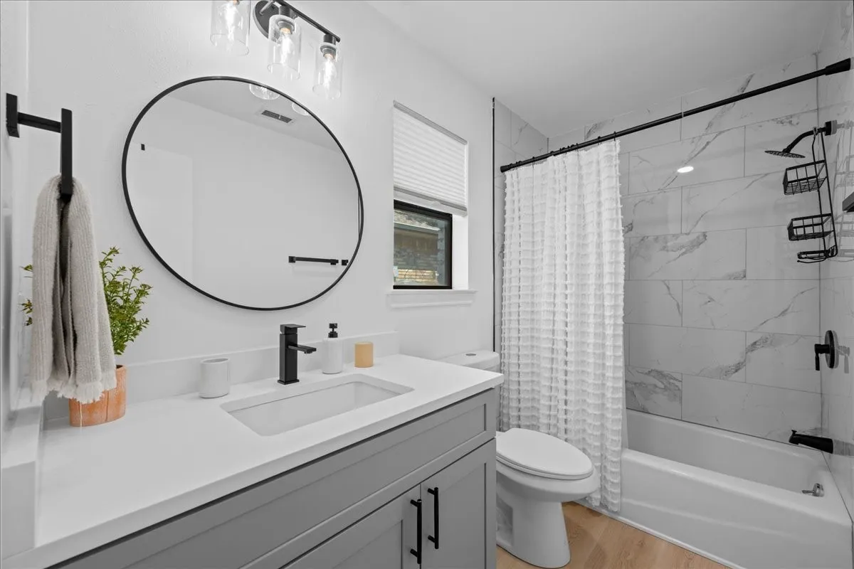 2nd Primary bathroom featuring a gray vanity with white countertop, integrated rectangular sink, matte black fixtures, and a shower with tile surround