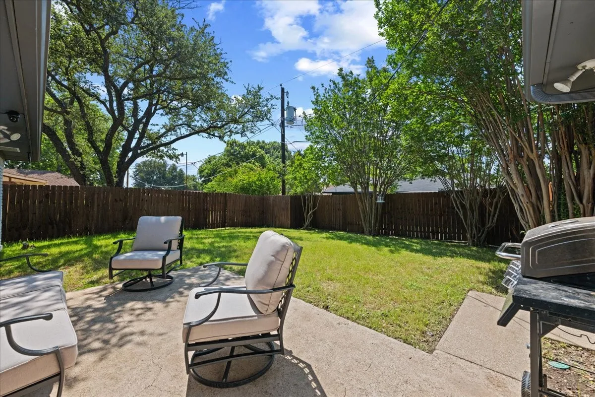 Expansive backyard featuring a concrete patio, a privacy fence, and mature trees