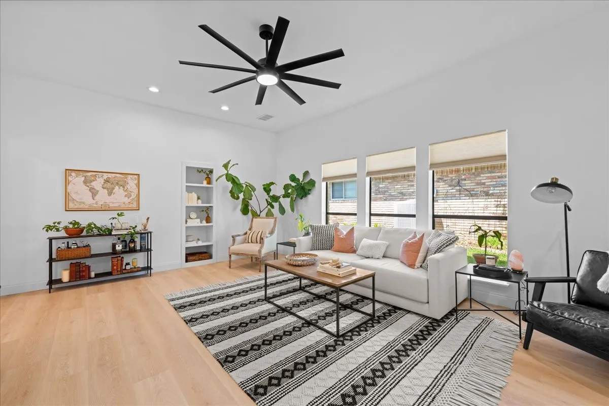 High ceilings with recessed lighting, wood-finish flooring, built-in shelving, and large windows with privacy shades