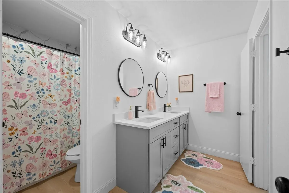 Jack & Jill has dual vanity with undermount sinks, matte black fixtures, and circular mirrors