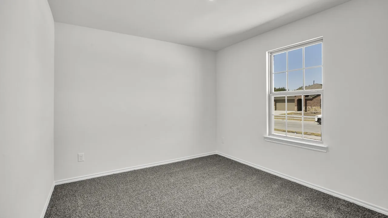 Spacious room featuring neutral carpeting and a single window with grid muntins