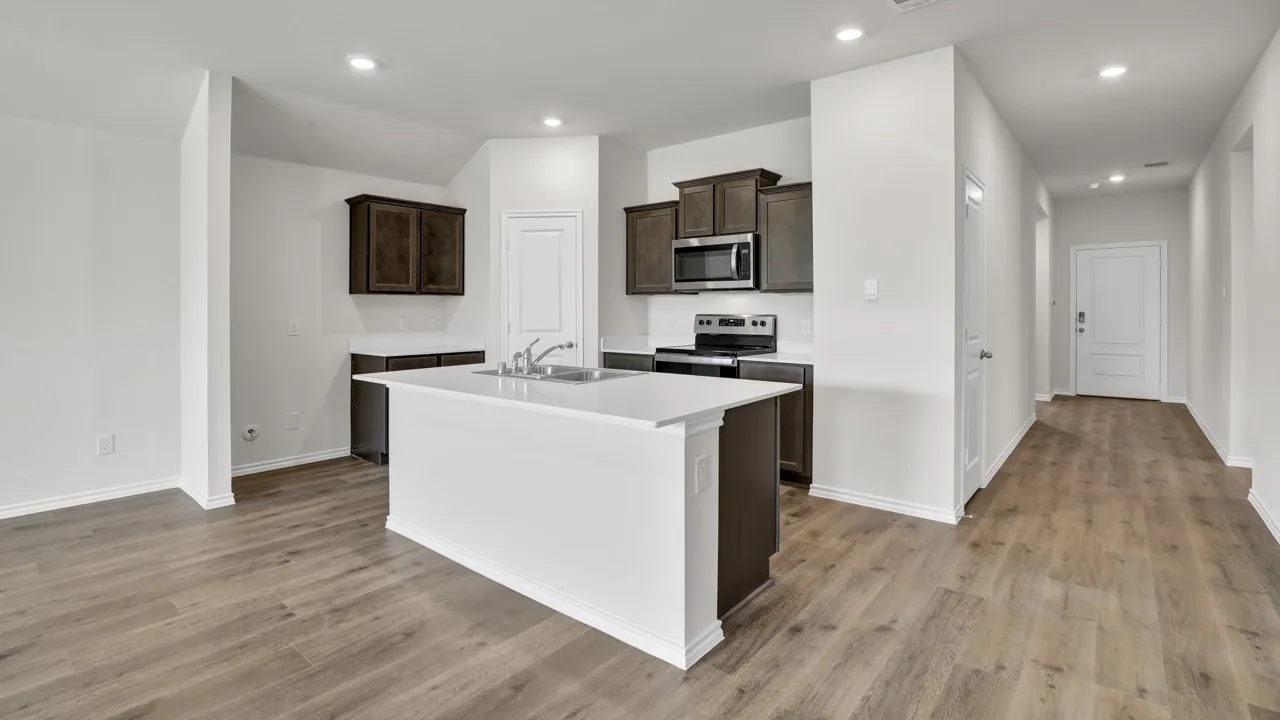 Open-concept kitchen featuring dark wood cabinetry, white countertops, and a central island with an integrated sink