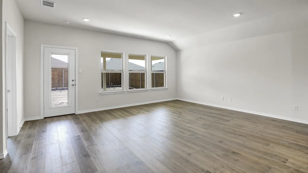 Spacious room featuring wood-finish flooring, white walls, multiple windows, and recessed lighting