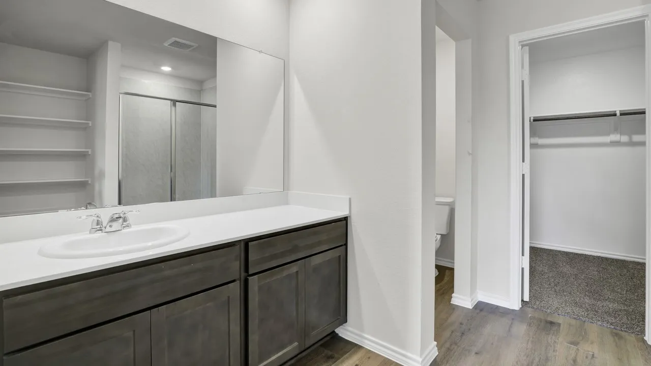Dual-sink vanity with white countertop, dark wood-finish cabinetry, and an integrated mirror