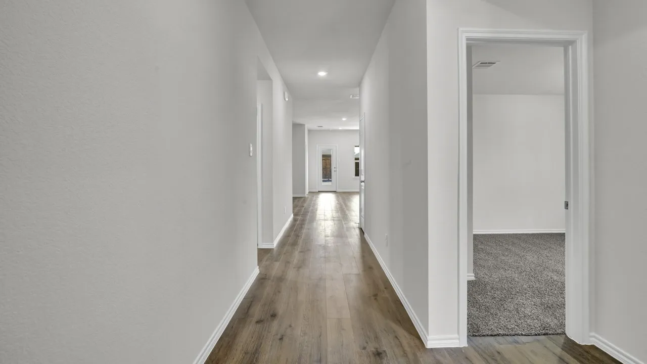 Hallway featuring wood-finish flooring, recessed lighting, white walls, and a doorway opening to a carpeted room