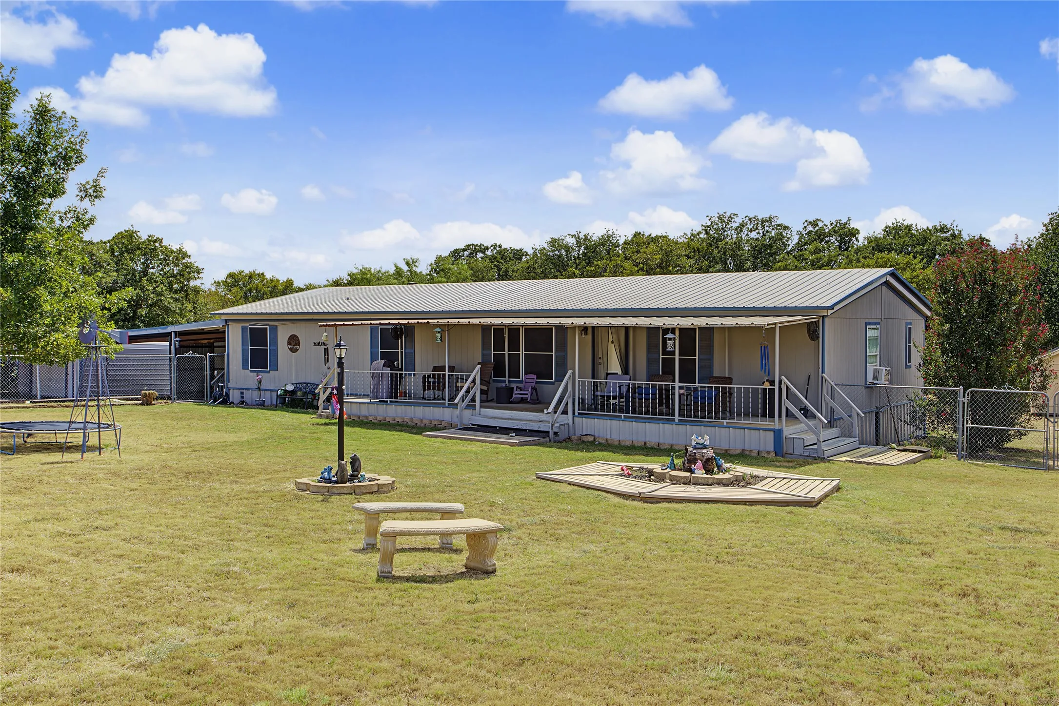 Expansive front yard with a covered porch, metal roof, and perimeter fencing