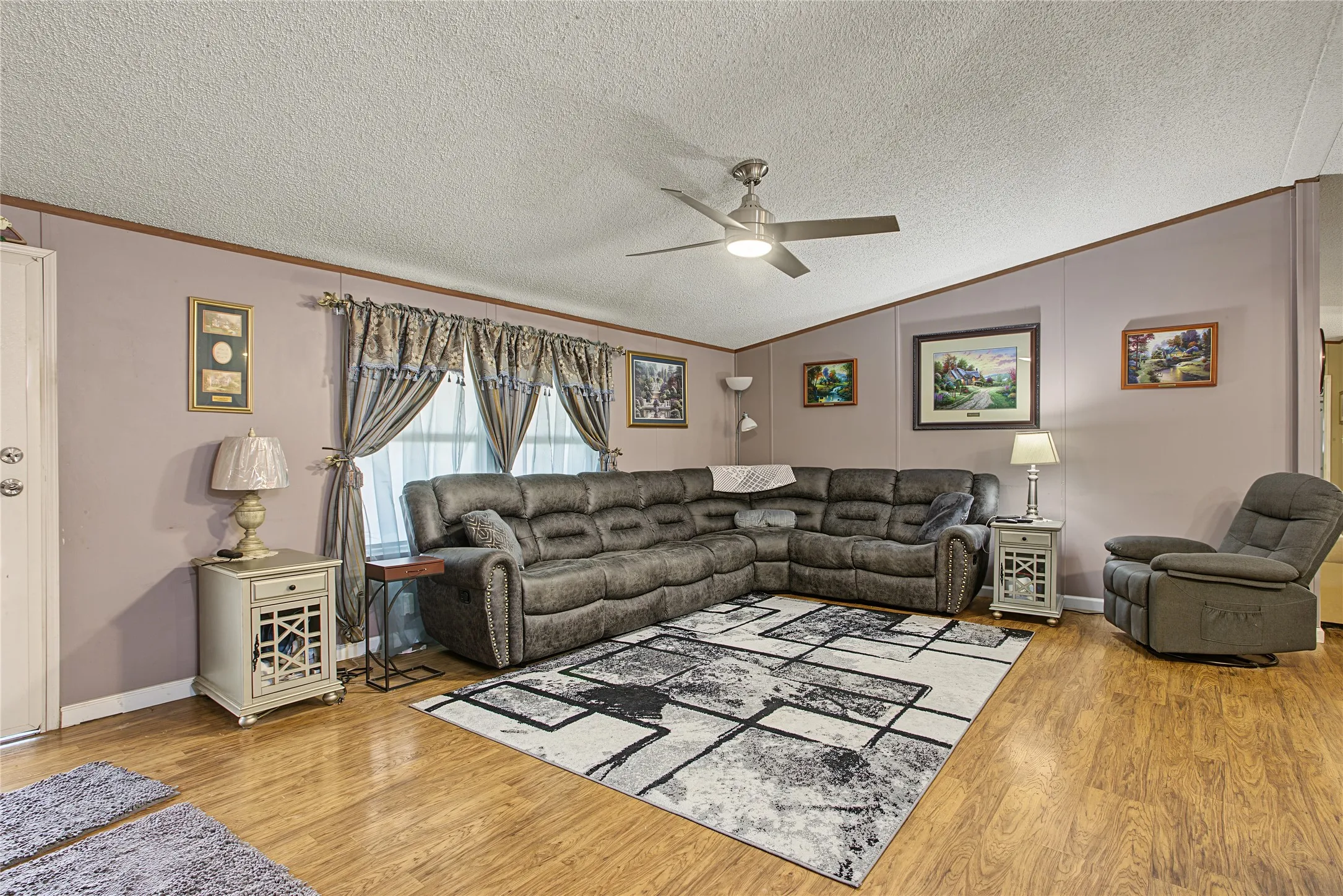 Wood-finish flooring, ceiling fan, and window with treatments
