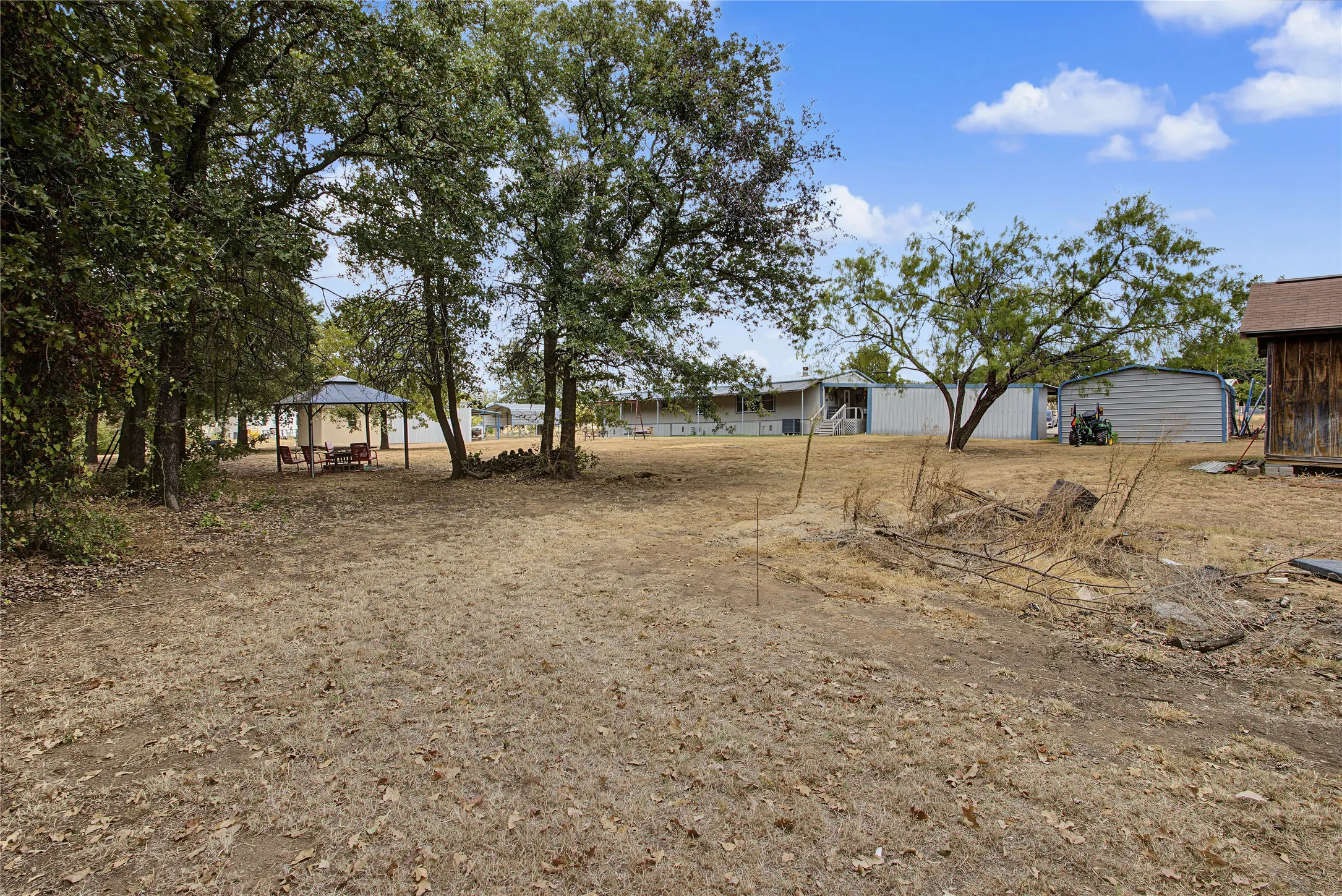 Expansive outdoor space featuring mature trees, a detached gazebo, and a storage shed