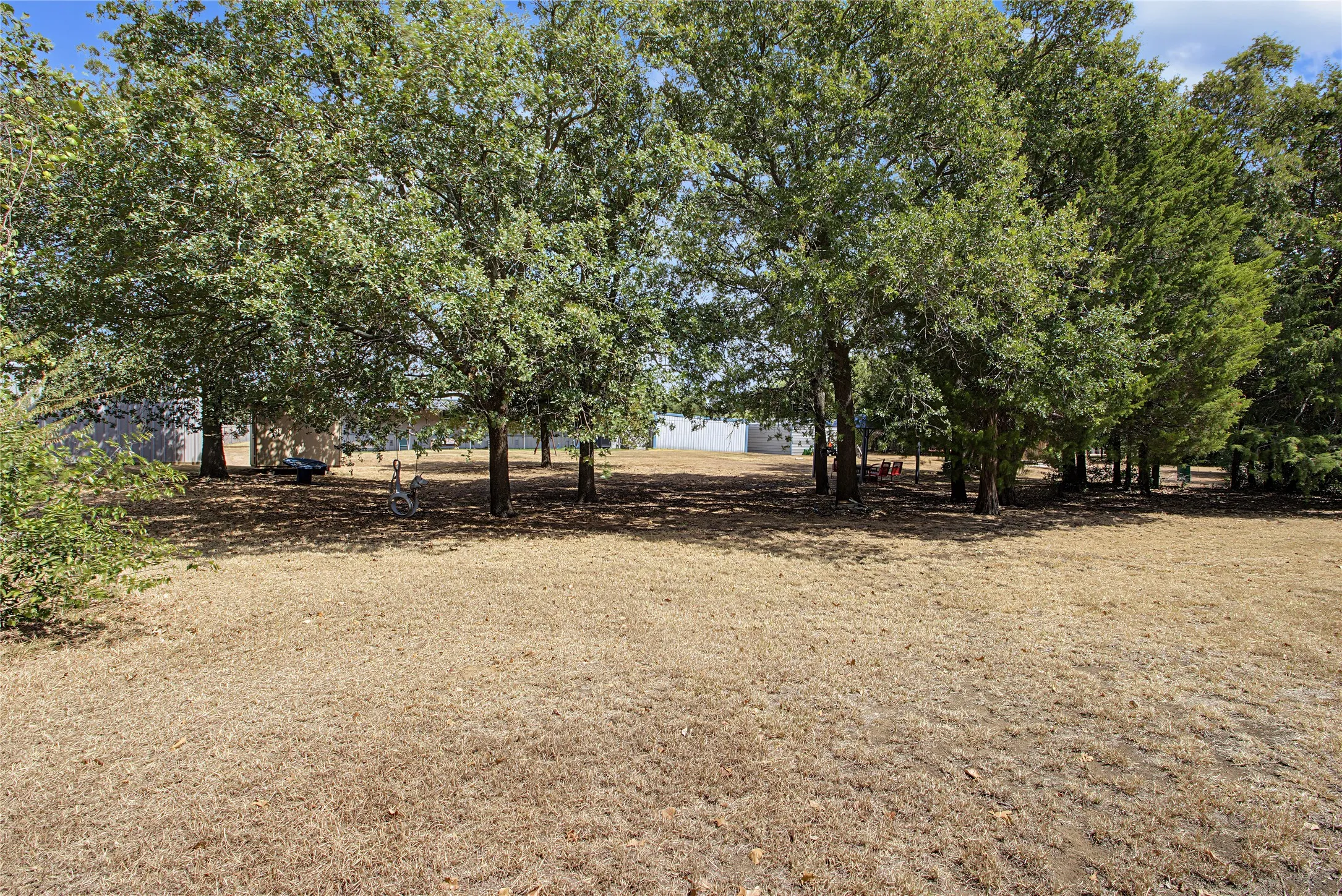 Expansive outdoor space featuring mature trees and a substantial open area