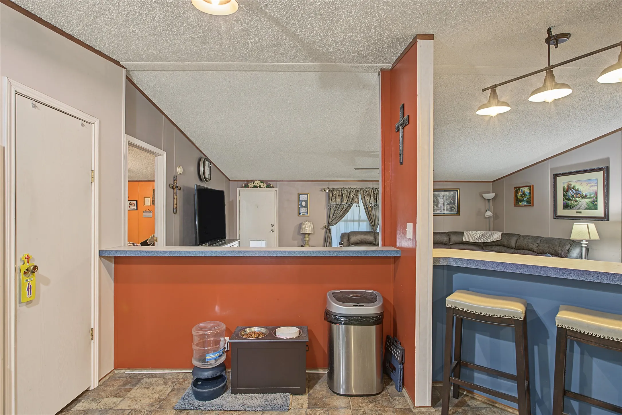 Two-tone breakfast bar with accent wall, overhead track lighting, and wood-finish flooring