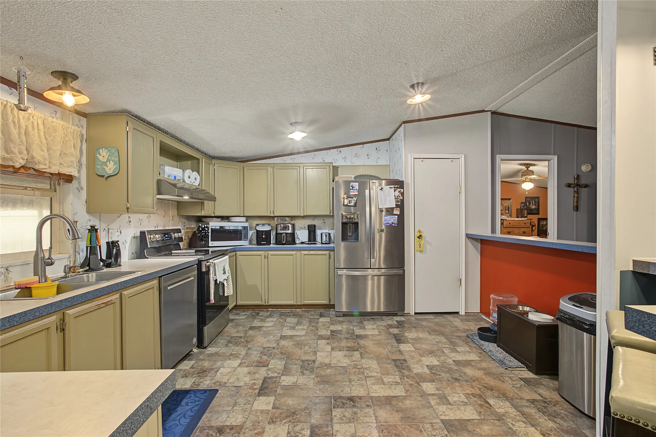 Kitchen featuring extensive cabinetry, resilient flooring, stainless steel appliances, a double basin sink, and recessed lighting