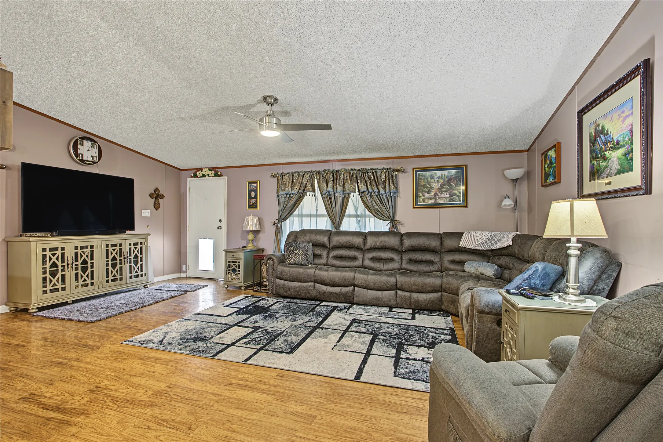 Wood-finish flooring throughout, ceiling fan with integrated lighting, and a neutral wall color