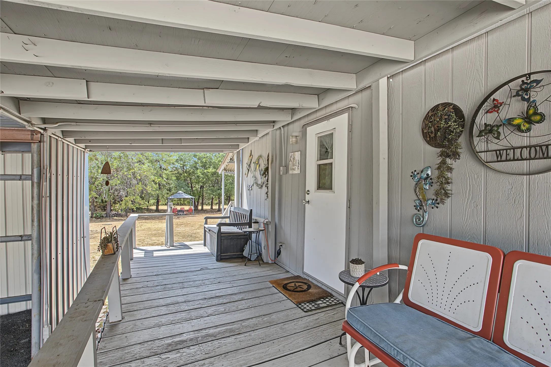 Covered wood-plank porch with white siding exterior and a white entry door with glass inserts