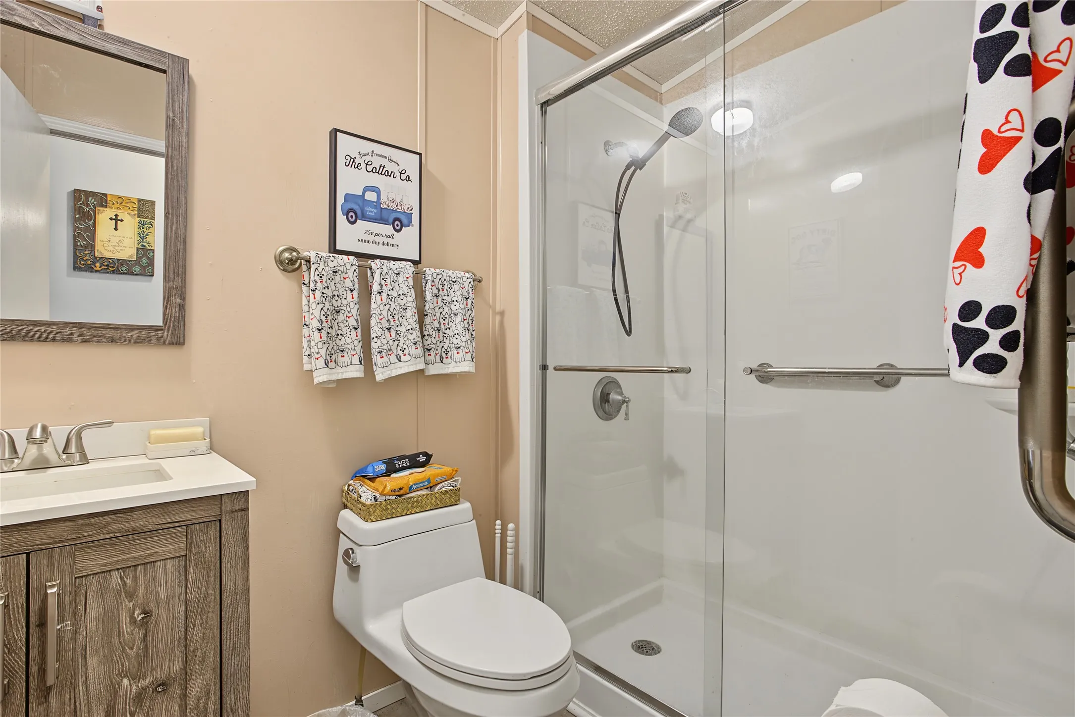 White shower surround with a glass enclosure, brushed nickel hardware, and grab bars