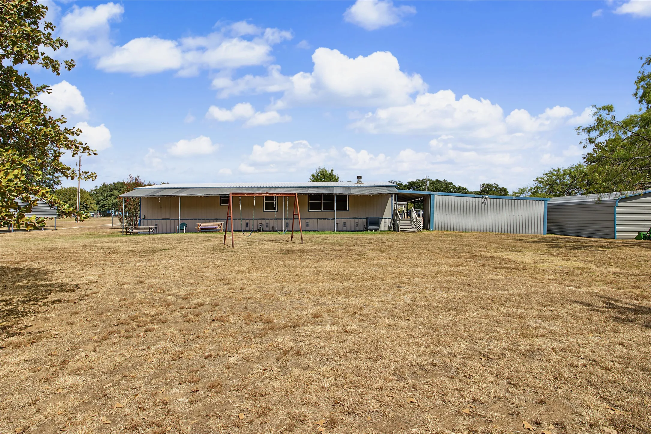 Expansive yard with a manufactured home featuring a covered porch and exterior siding
