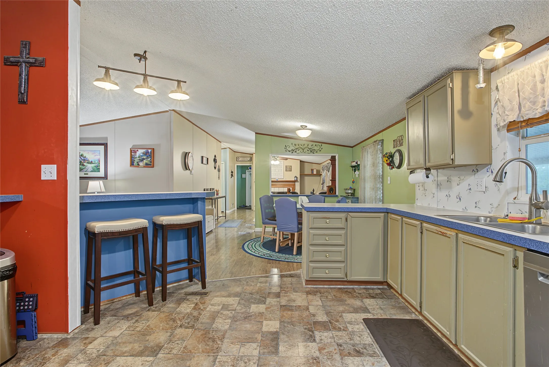 Expansive kitchen featuring wood-finish flooring, light-toned cabinetry, and a double basin sink with a gooseneck faucet