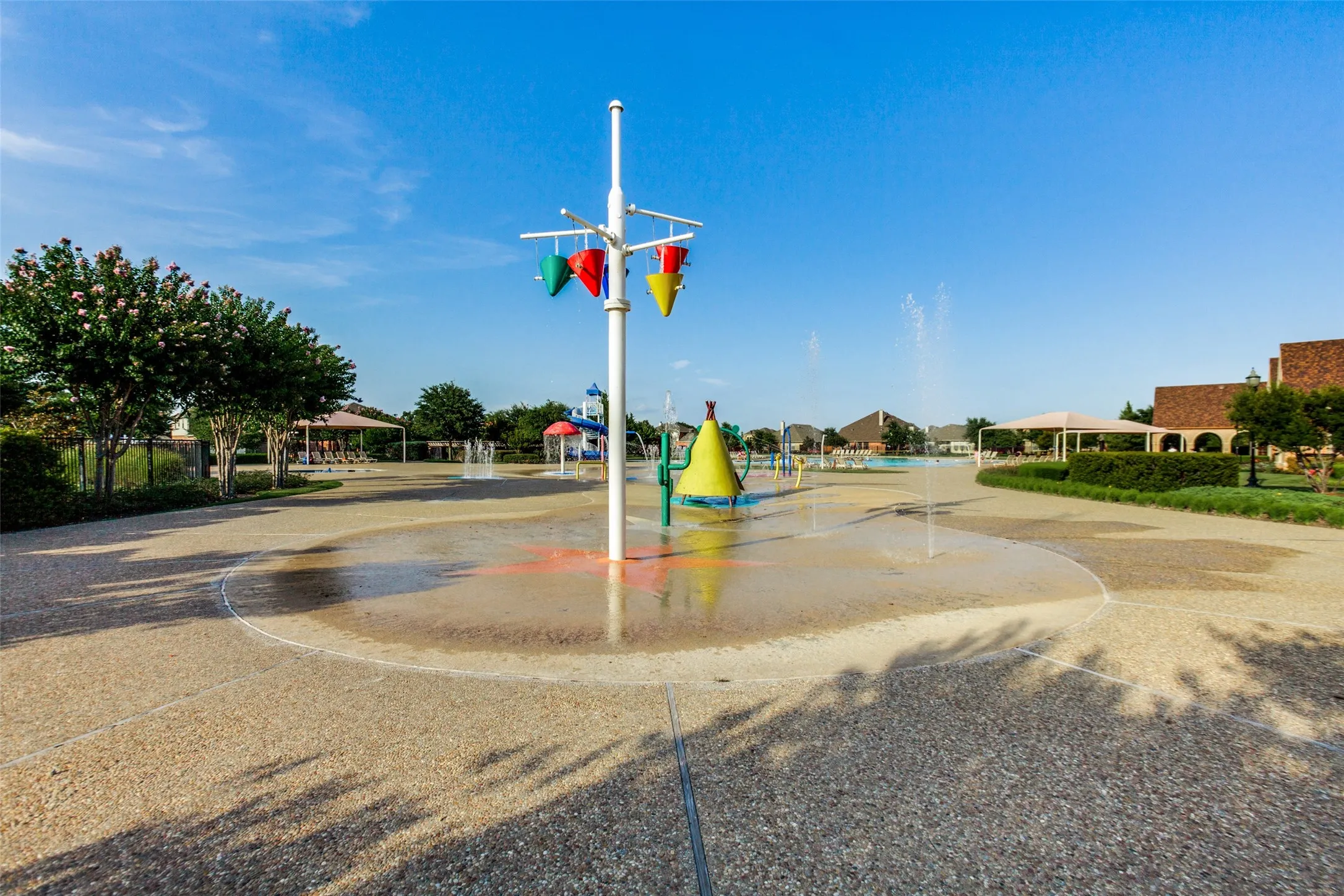 Community splash pad with multiple water features, hardscape surfacing, and surrounding landscaping