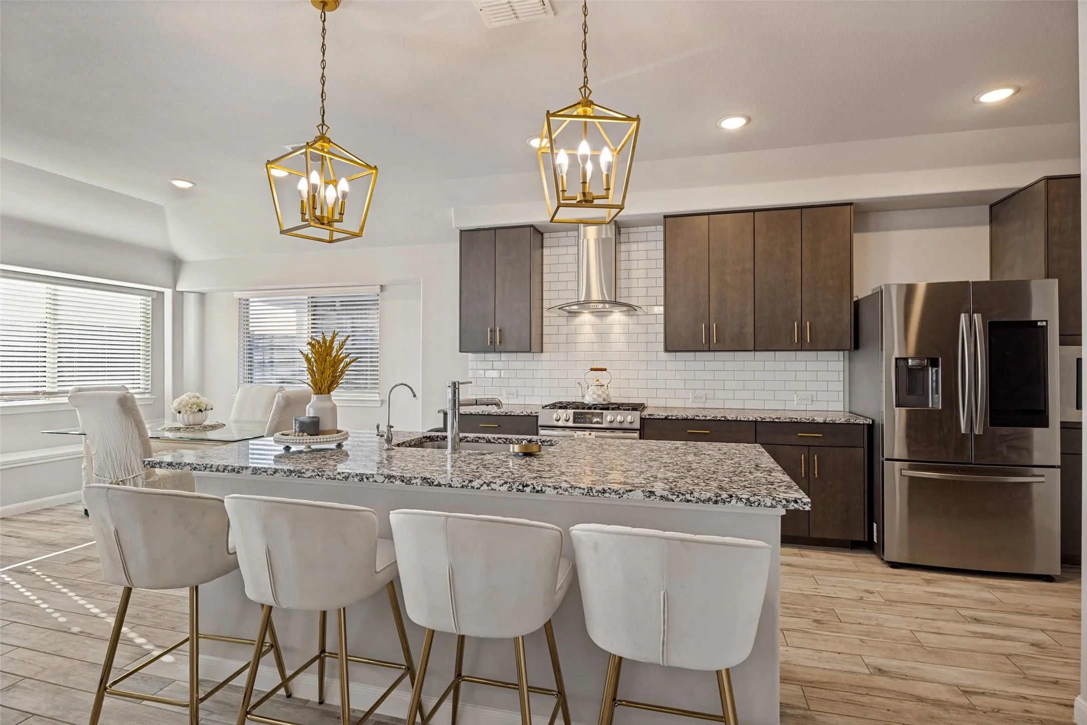 Kitchen featuring a large island with granite countertops, stainless steel appliances, wood-finish flooring, and white subway tile backsplash