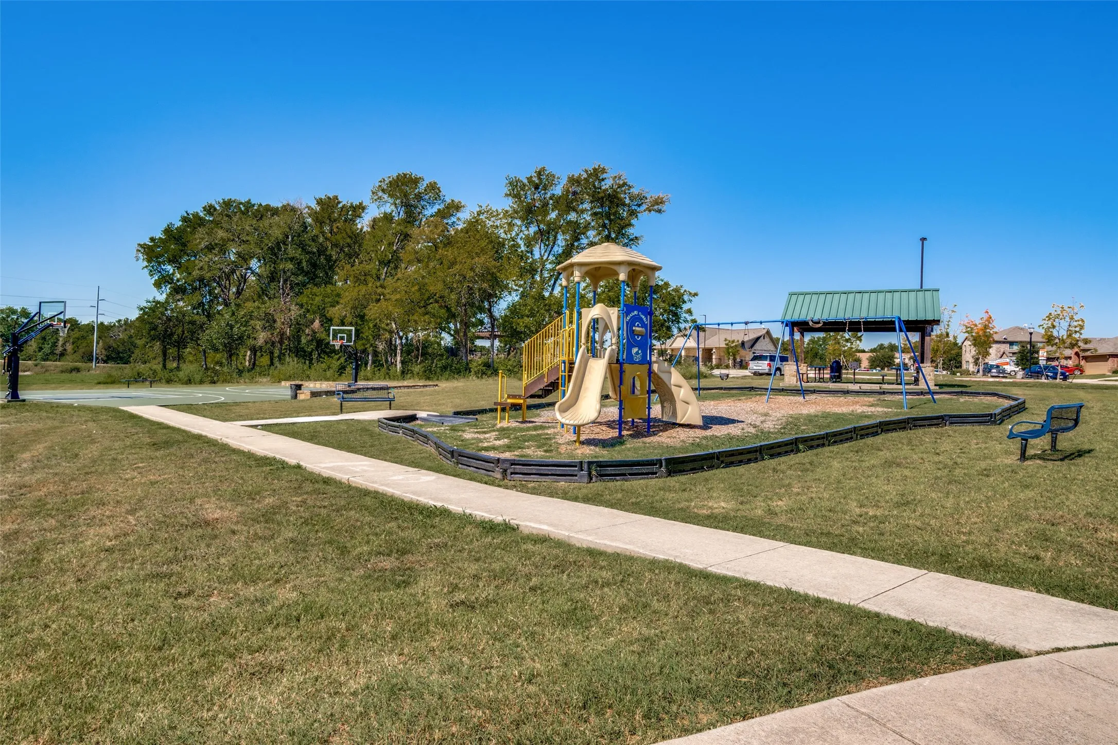 Community playground featuring multiple slides, swing sets, and a covered picnic area