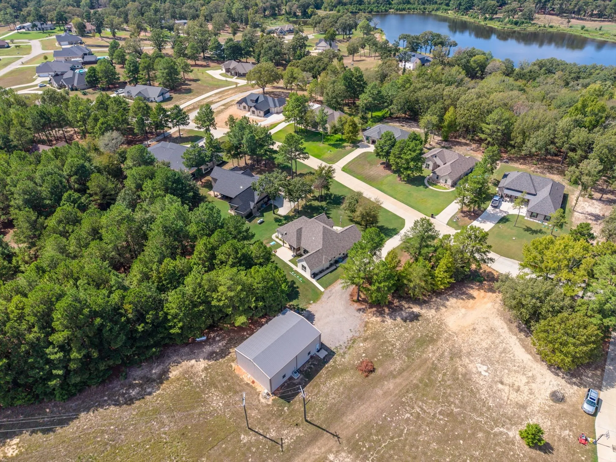 Expansive lot featuring a standalone metal building, surrounded by mature trees and a paved driveway