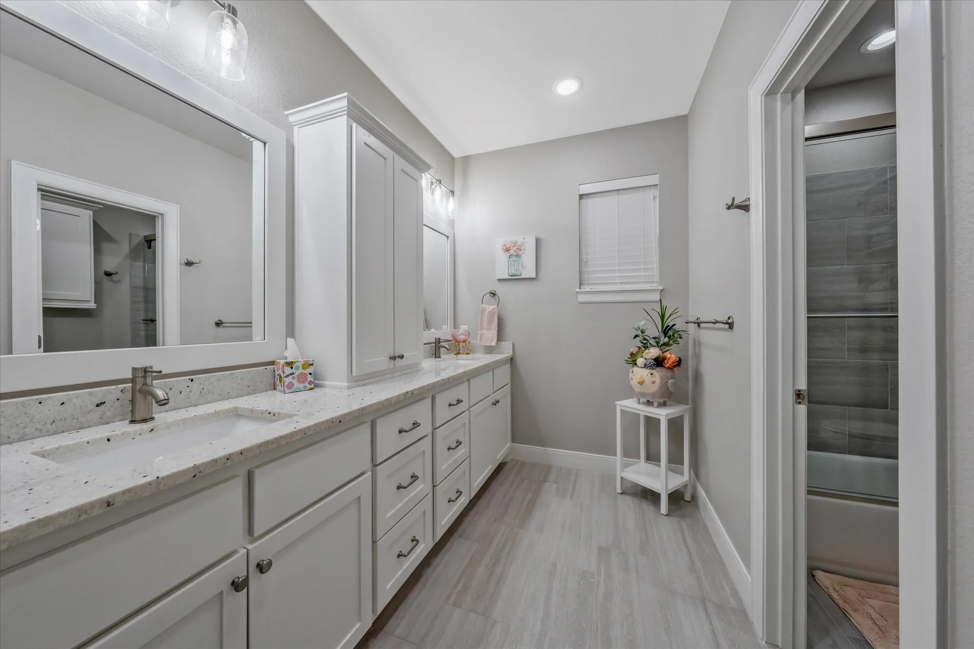 Double vanity with integrated sinks, white cabinetry, speckled countertop, and wood-finish flooring