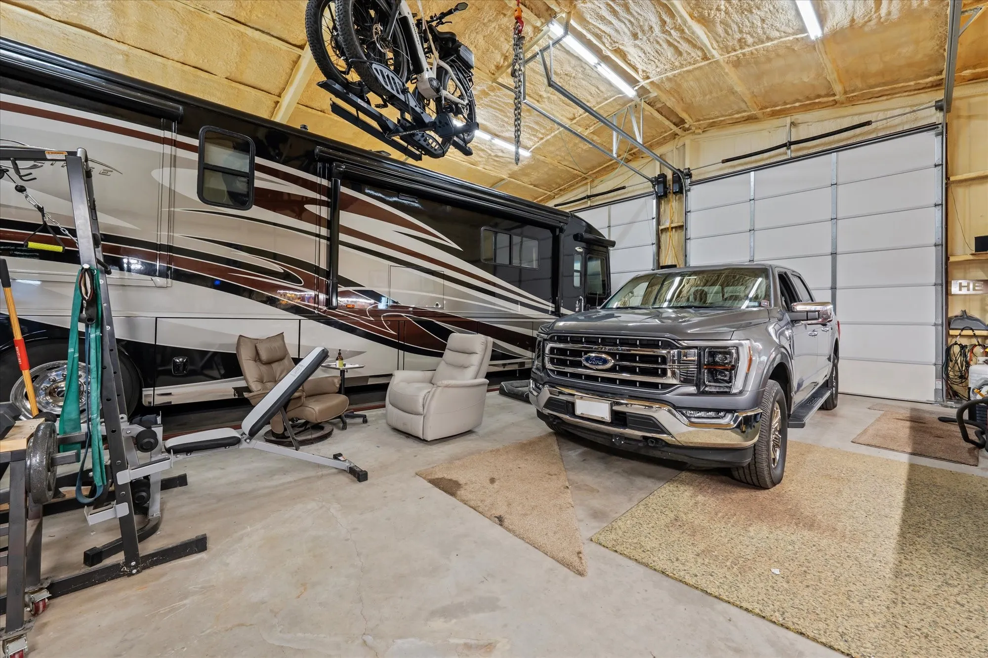 High ceilings with exposed insulation, concrete flooring, and multiple overhead doors