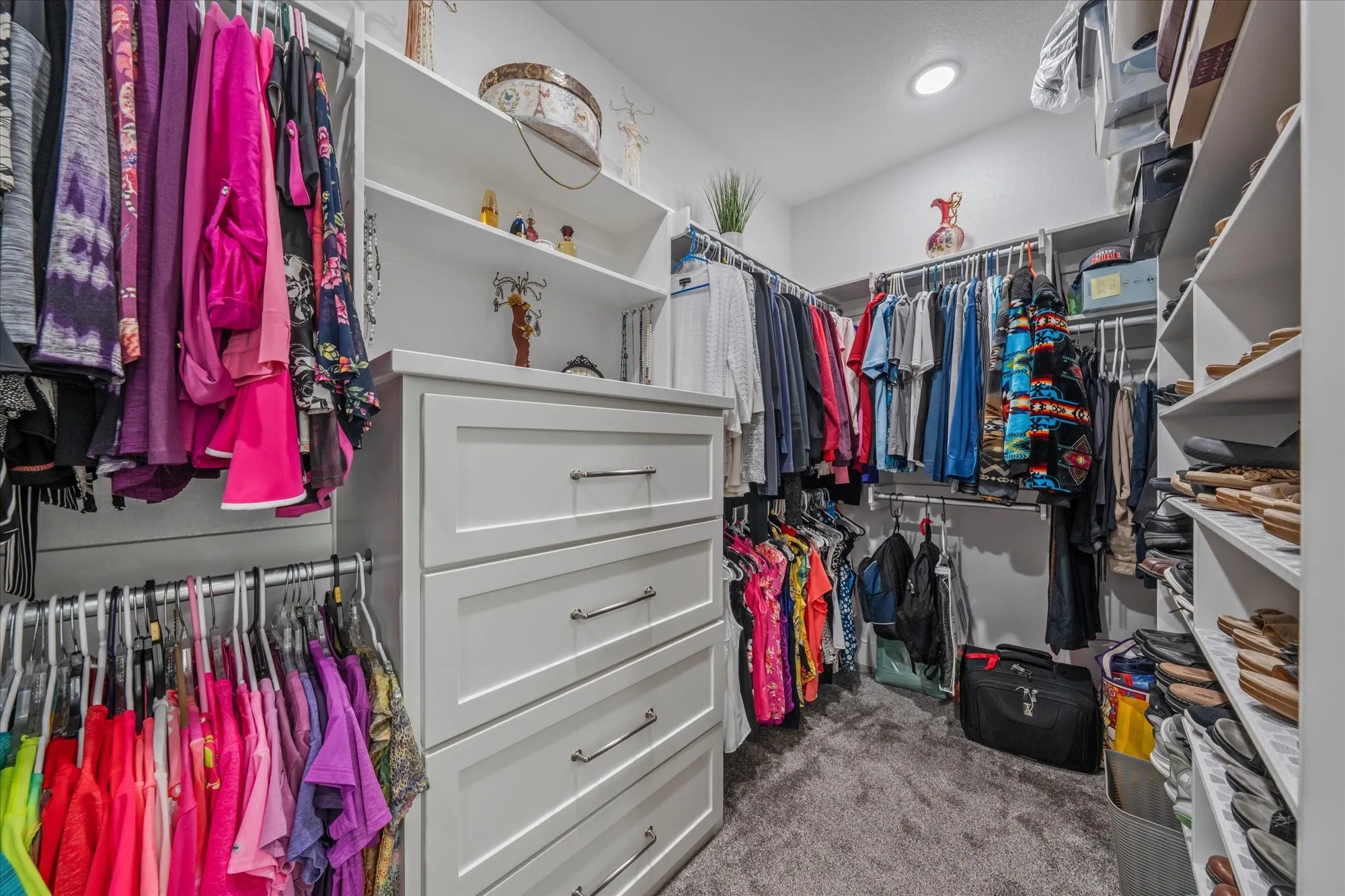 Walk-in closet featuring built-in shelving, hanging rods, and a multi-drawer dresser unit with chrome hardware