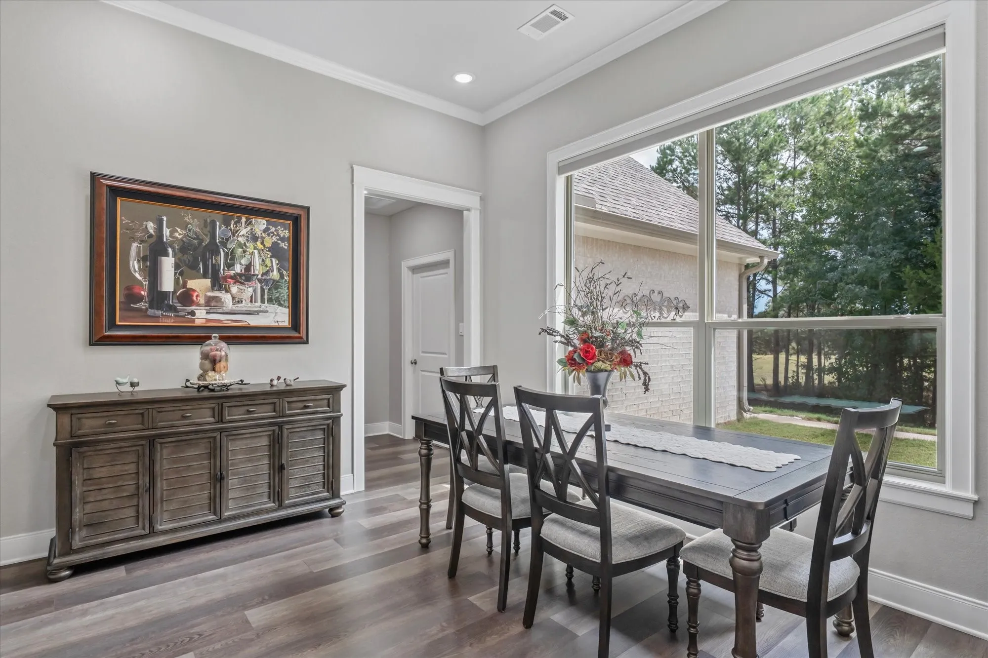 Expansive window with white trim, wood-finish flooring, and crown molding