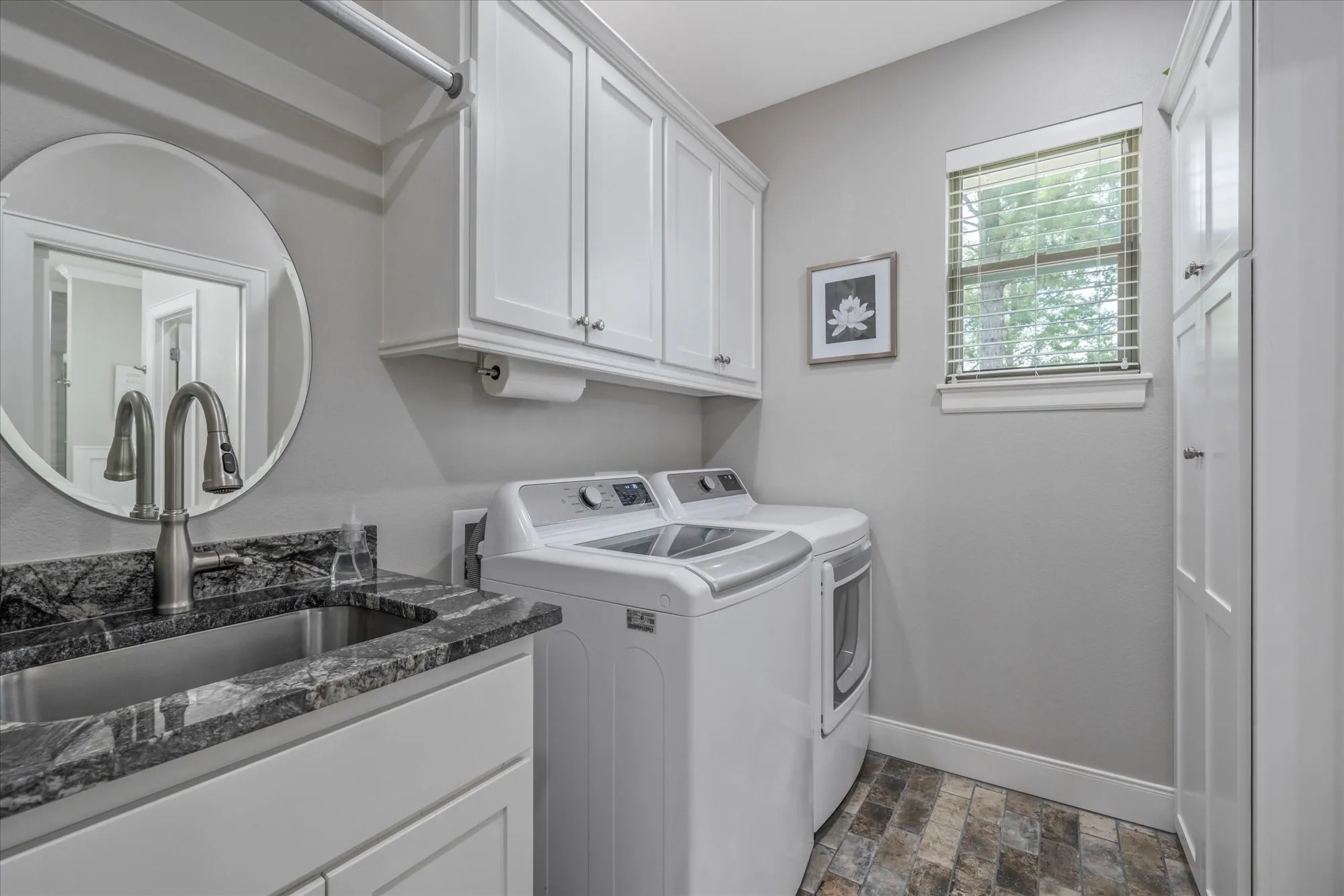Utility room featuring a built-in sink with a countertop, white cabinetry, wood-finish flooring, and a window with blinds