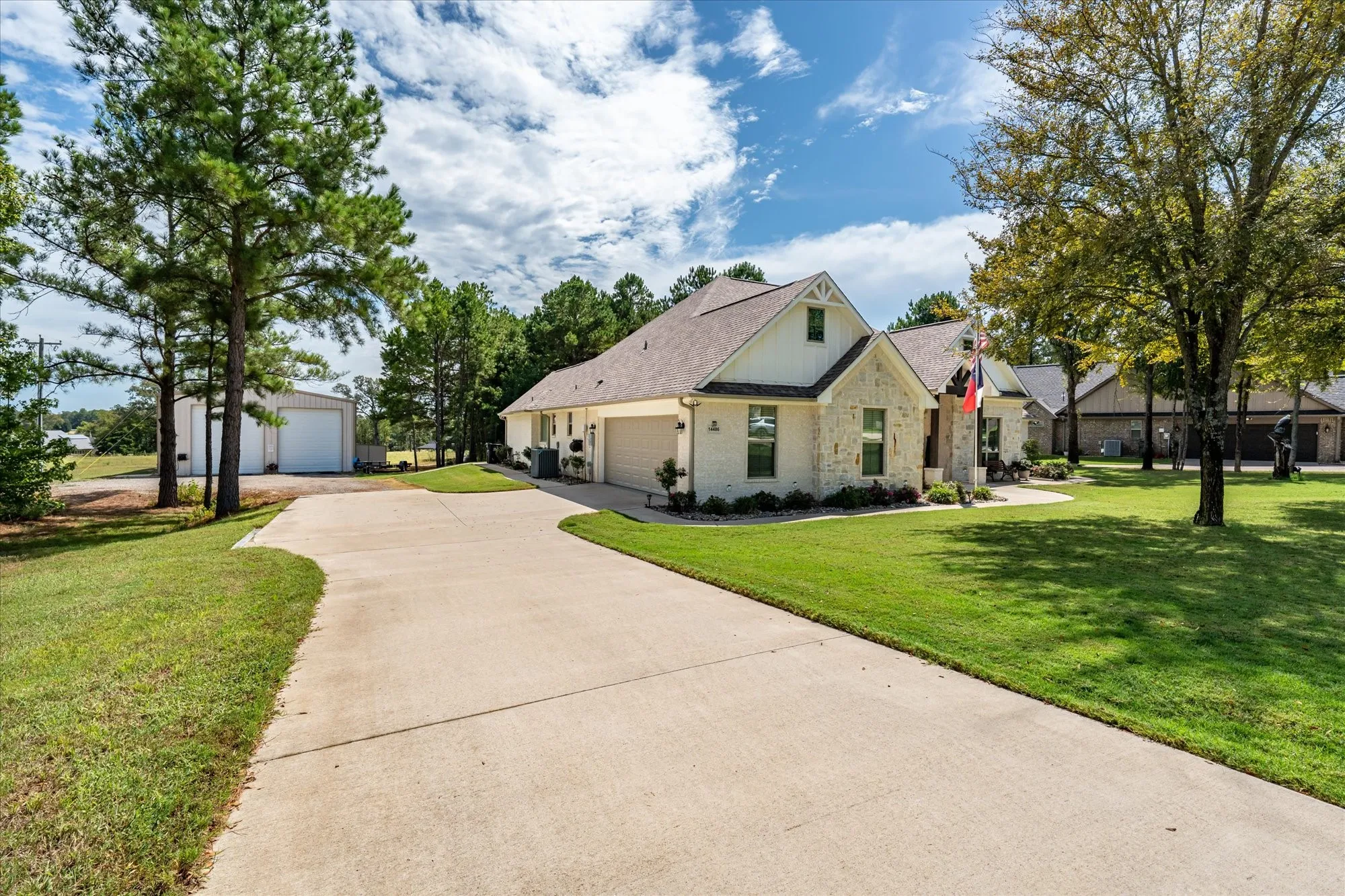 Exterior featuring stone and siding finishes, gabled rooflines, an attached garage, and a concrete driveway