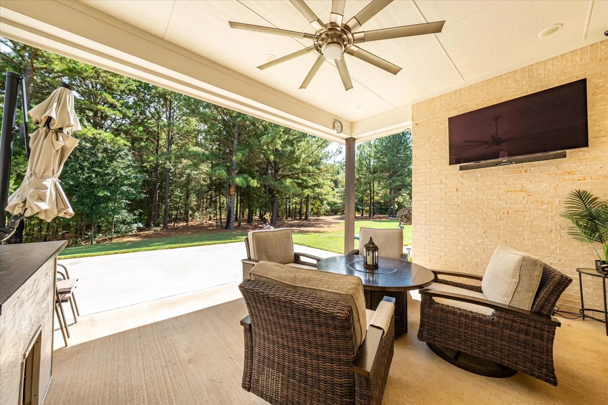 Covered patio featuring a ceiling fan, a mounted television, a textured accent wall, and a concrete floor