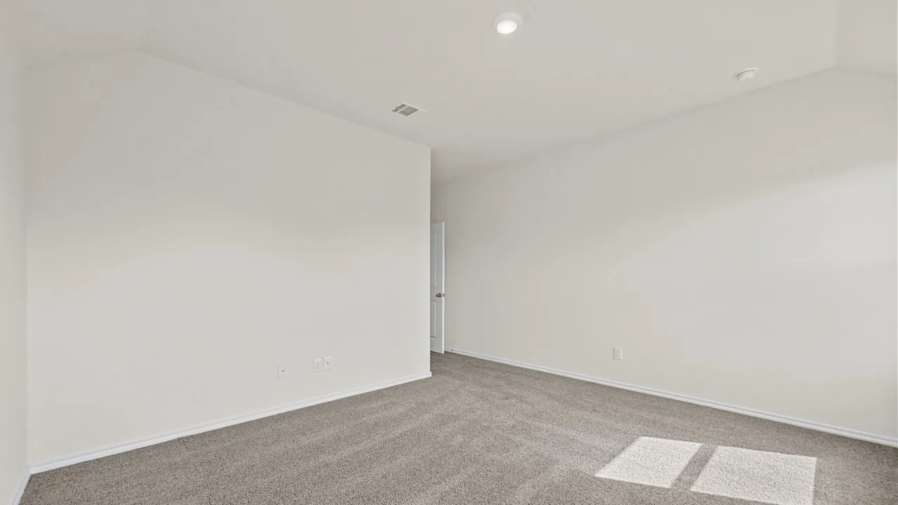 Recessed lighting illuminates neutral painted walls and gray carpeting