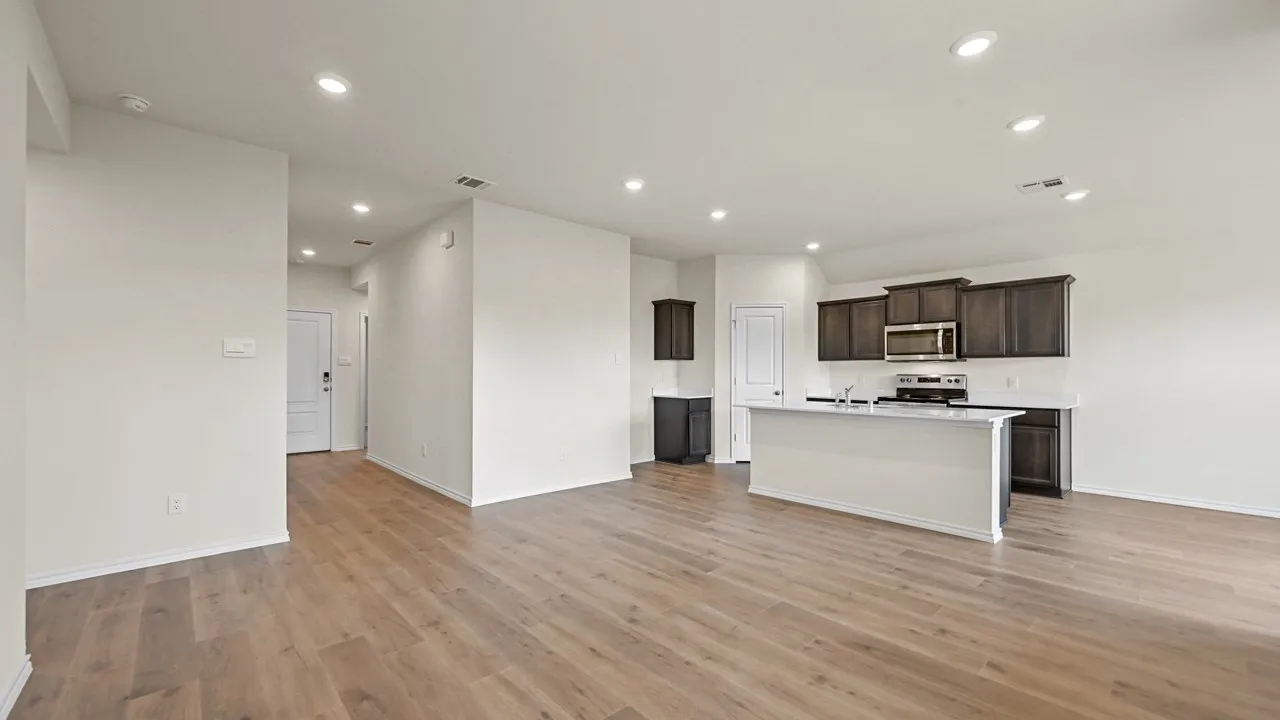 Open concept living area featuring wood-finish flooring, recessed lighting, and a kitchen with dark cabinetry, white countertops, and a central island