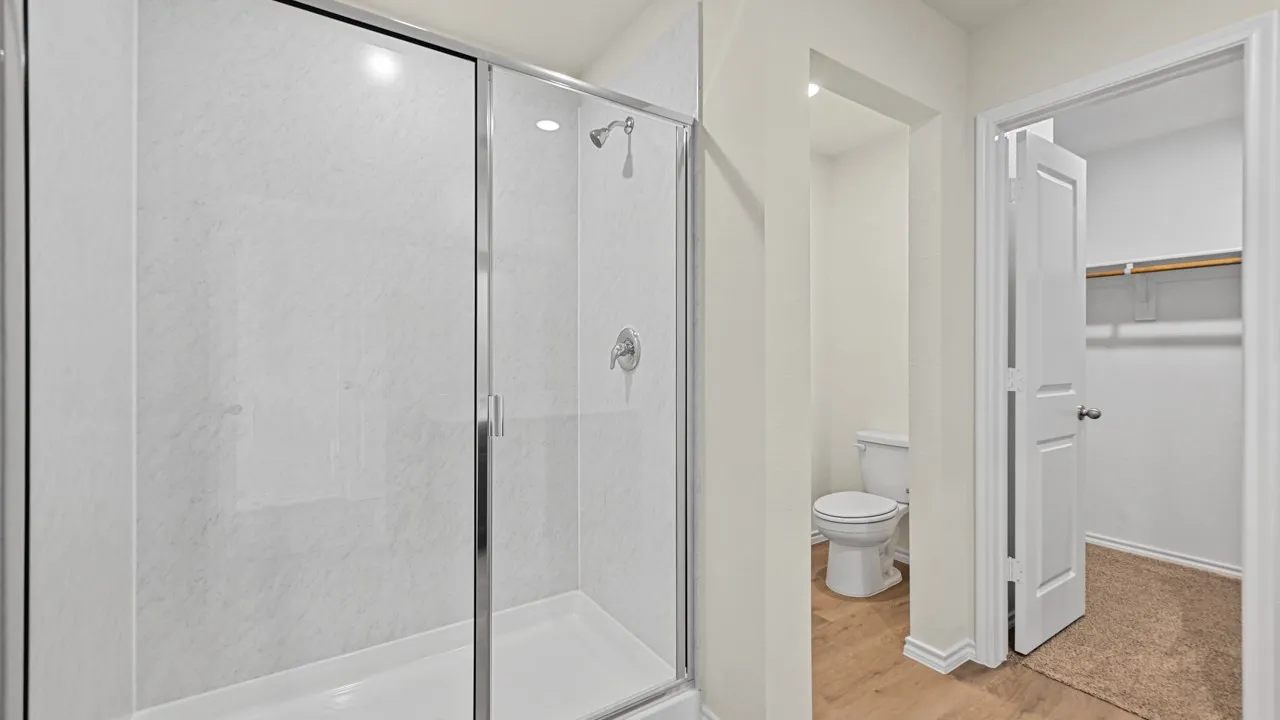 Enclosed shower with clear glass door and white textured wall panels