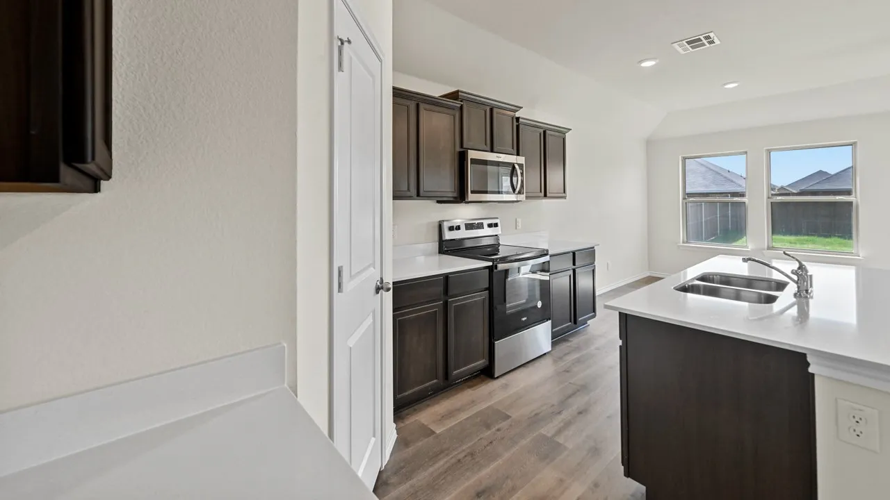Kitchen featuring dark wood-finish cabinetry, stainless steel appliances, solid surface countertops, and wood-finish flooring