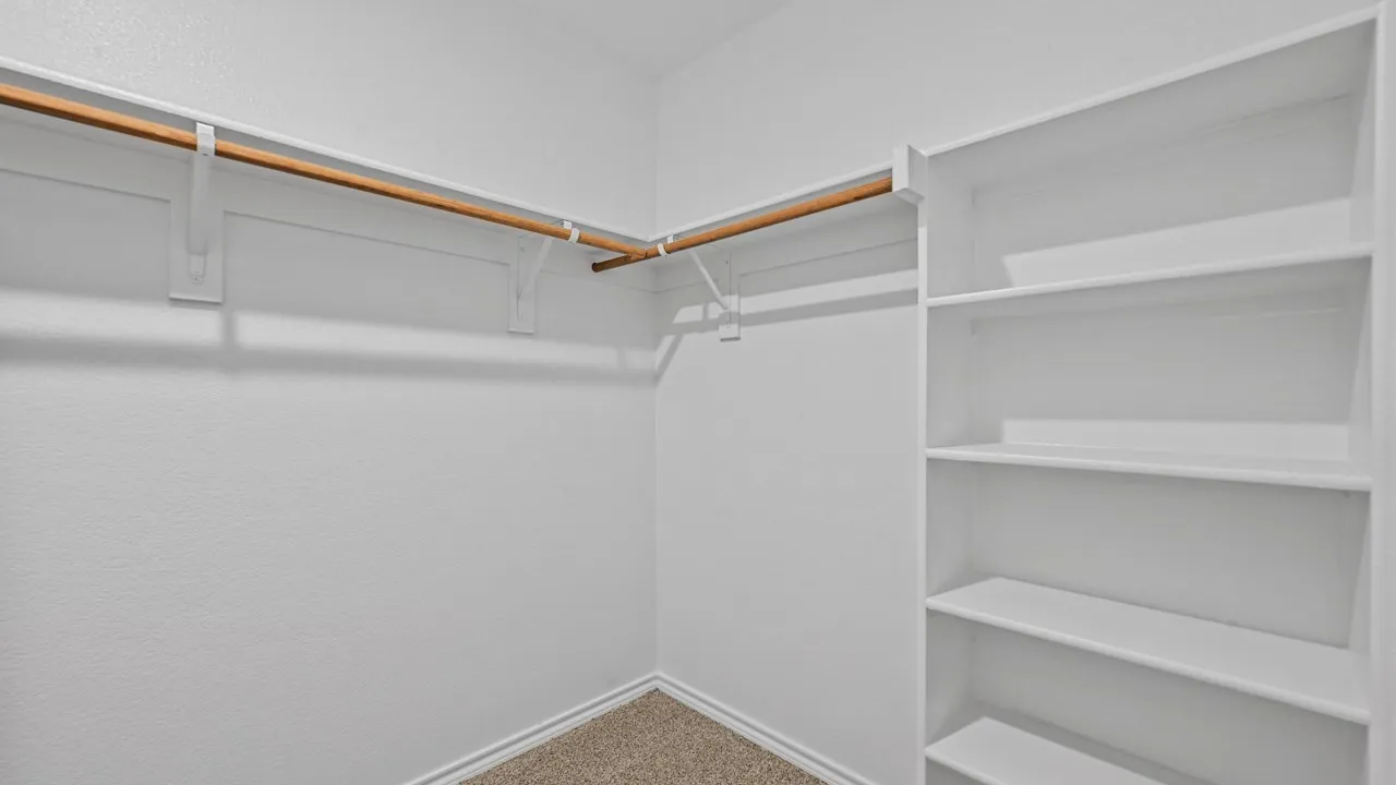 Walk-in closet featuring built-in shelving, wood rods, and carpet flooring