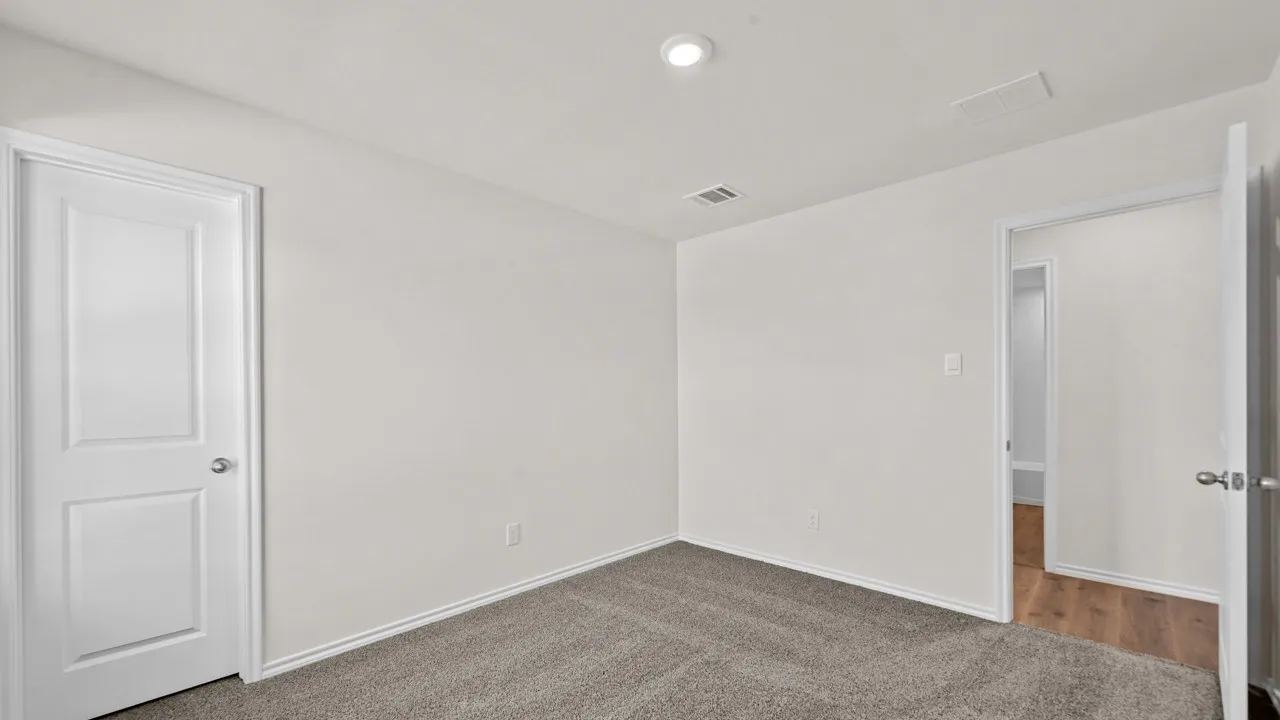 Recessed ceiling lighting, white interior doors, wood-finish flooring visible through doorway, and light gray carpet