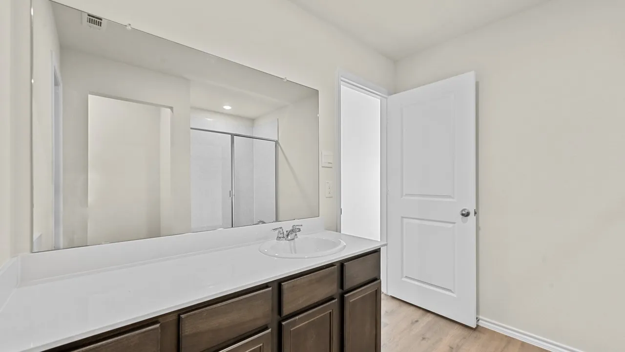 Integrated vanity with an undermount sink, a chrome faucet, and a large wall-mounted mirror